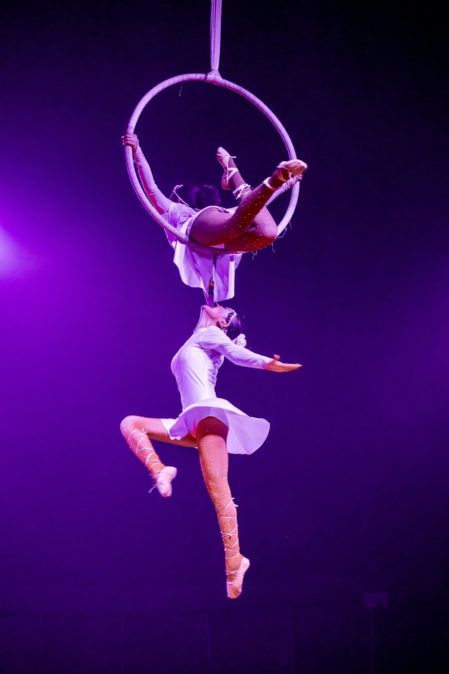 Acrobata no aro aéreo sob luz roxa