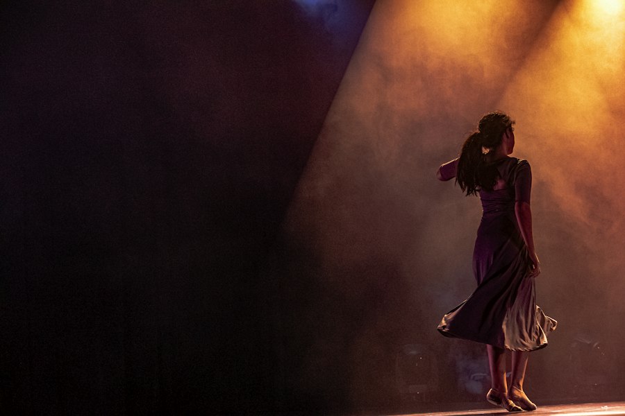 Bailarina de vestido escuro sob a luz do palco