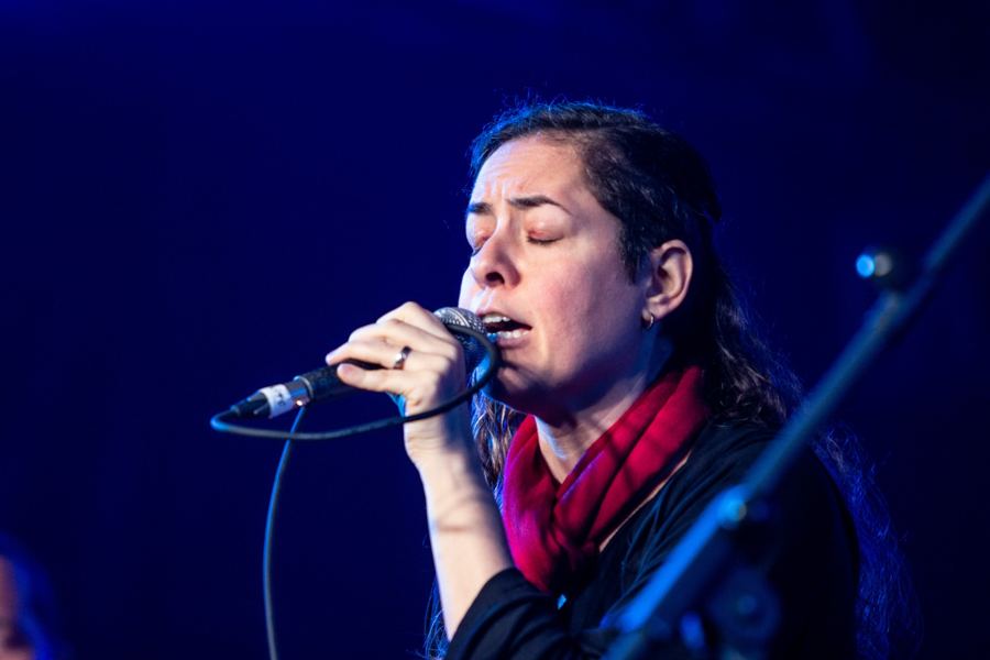 Carla cantando, com cachecol vermelho